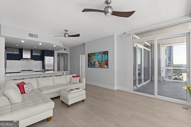 living room featuring ceiling fan, sink, and light hardwood / wood-style flooring