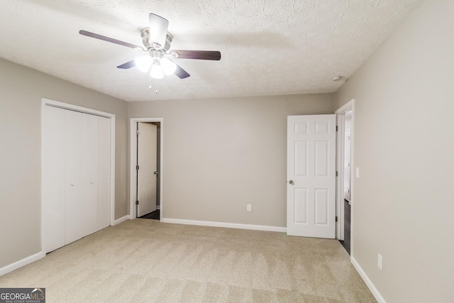 unfurnished bedroom featuring a closet, ceiling fan, light carpet, and a textured ceiling