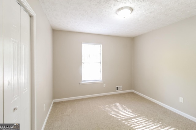 carpeted empty room with a textured ceiling