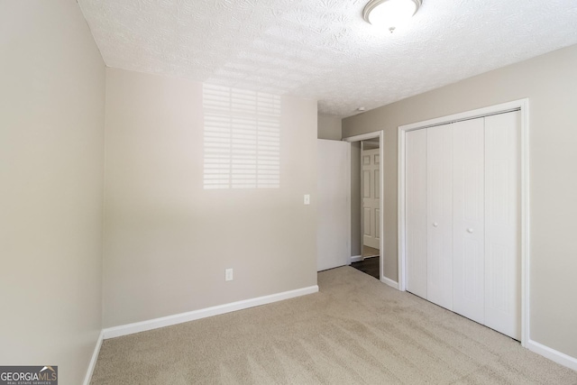 unfurnished bedroom with light carpet, a closet, and a textured ceiling