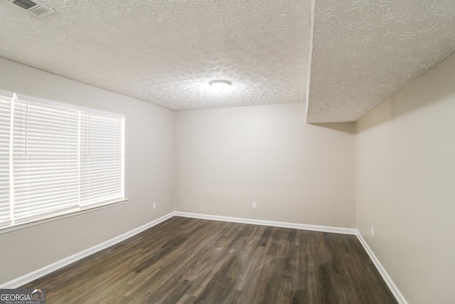 spare room featuring dark wood-type flooring and a textured ceiling