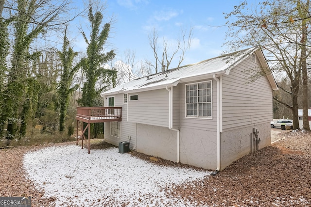 snow covered property with a wooden deck and central air condition unit