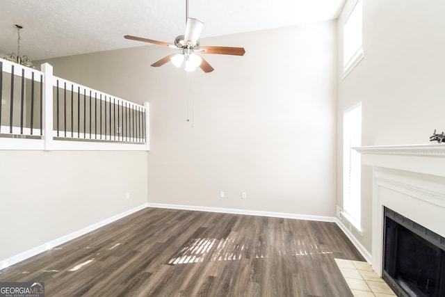 unfurnished living room featuring ceiling fan, dark wood-type flooring, and high vaulted ceiling