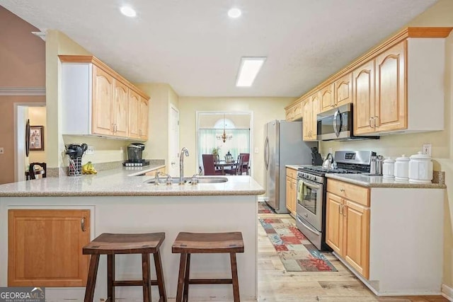 kitchen with sink, kitchen peninsula, light hardwood / wood-style flooring, stainless steel appliances, and light brown cabinets