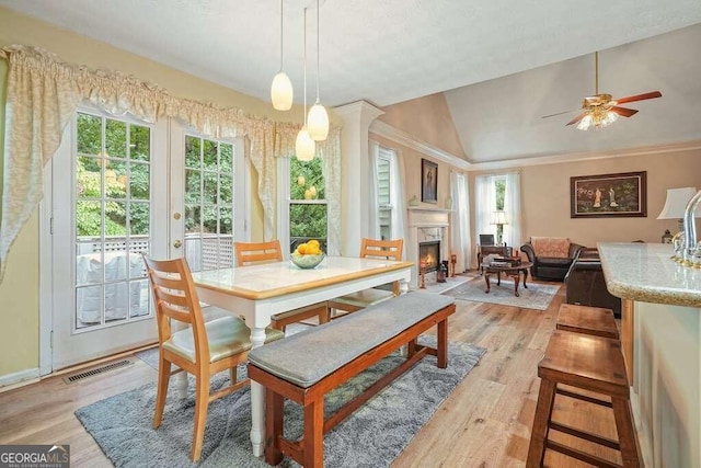 dining room with ornamental molding, light hardwood / wood-style floors, vaulted ceiling, and ceiling fan