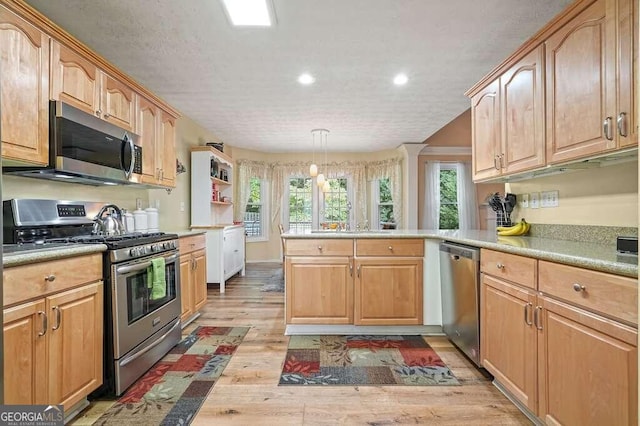 kitchen featuring hanging light fixtures, kitchen peninsula, a textured ceiling, stainless steel appliances, and light wood-type flooring