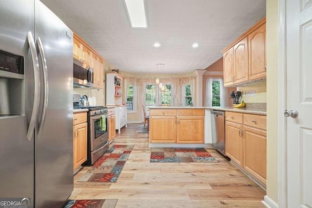 kitchen with light wood-type flooring, kitchen peninsula, stainless steel appliances, and decorative light fixtures