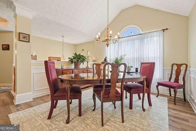 dining area with a notable chandelier, wood-type flooring, lofted ceiling, and a textured ceiling