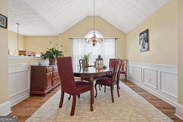 dining room with a notable chandelier, hardwood / wood-style floors, and a textured ceiling