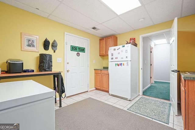 kitchen with a paneled ceiling, light tile patterned floors, and white refrigerator