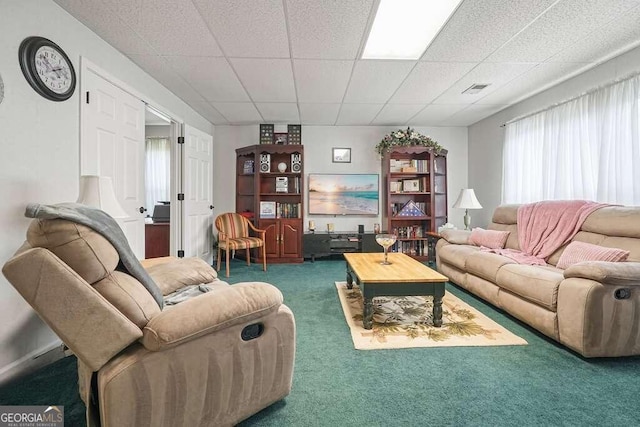 living room featuring a drop ceiling and dark colored carpet