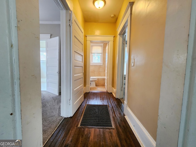 corridor featuring ornamental molding, wood finished floors, and baseboards