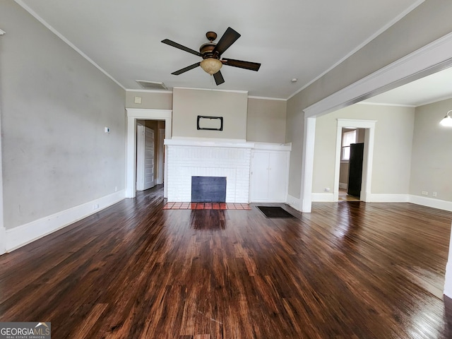 unfurnished living room featuring dark wood-style flooring, visible vents, baseboards, a brick fireplace, and crown molding