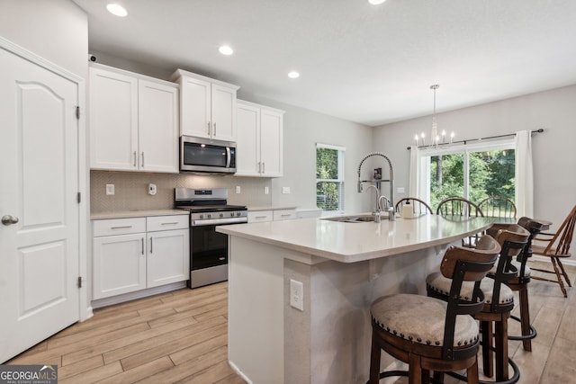 kitchen with decorative light fixtures, white cabinetry, appliances with stainless steel finishes, and tasteful backsplash