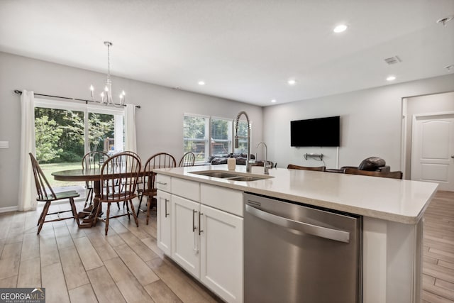 kitchen with light hardwood / wood-style flooring, a kitchen island with sink, dishwasher, sink, and decorative light fixtures