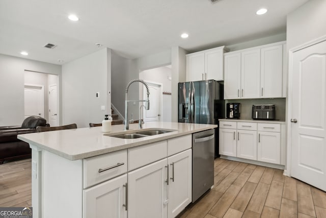 kitchen with appliances with stainless steel finishes, light hardwood / wood-style flooring, a kitchen island with sink, and sink