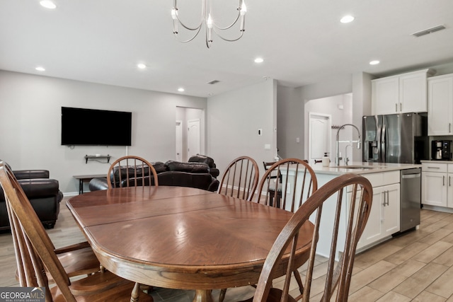 dining room featuring sink, light hardwood / wood-style flooring, and an inviting chandelier