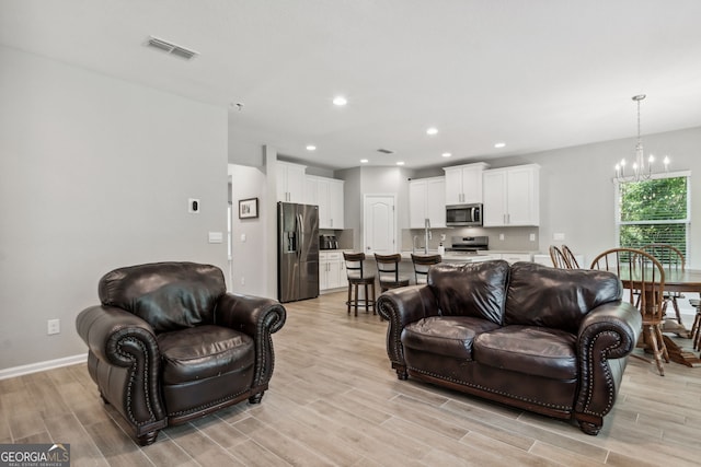 living room featuring a notable chandelier and light wood-type flooring