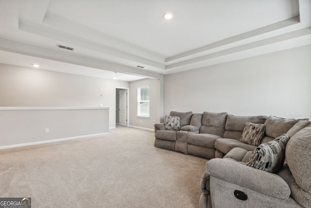 living room featuring light colored carpet and a tray ceiling