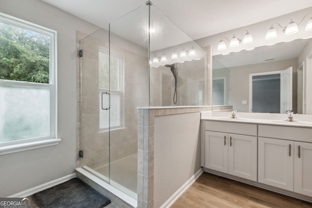 bathroom with dual vanity, wood-type flooring, and an enclosed shower