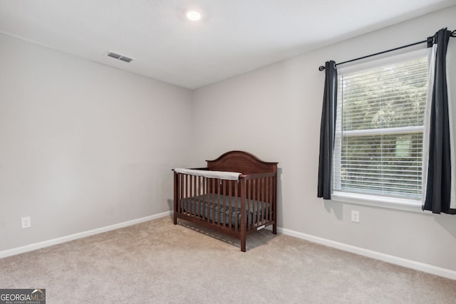 bedroom with a crib and light colored carpet