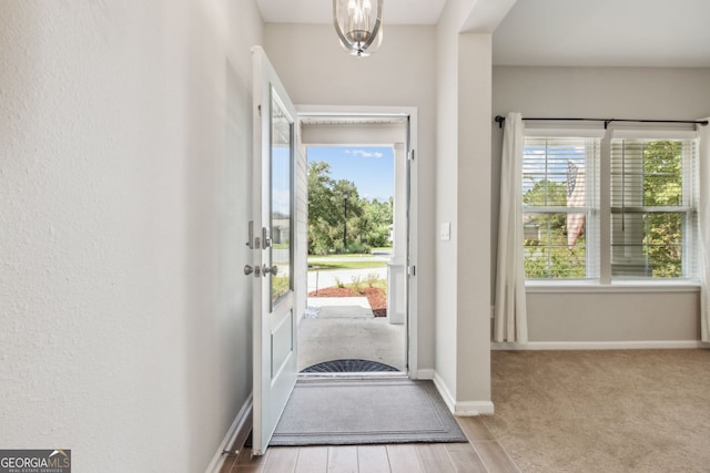 doorway to outside featuring a notable chandelier, a healthy amount of sunlight, and light carpet