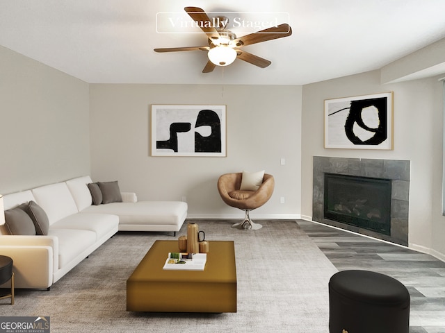 living room with ceiling fan, a tile fireplace, and wood-type flooring