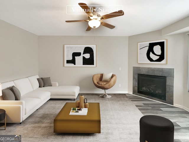 living room featuring a fireplace, wood finished floors, a ceiling fan, and baseboards