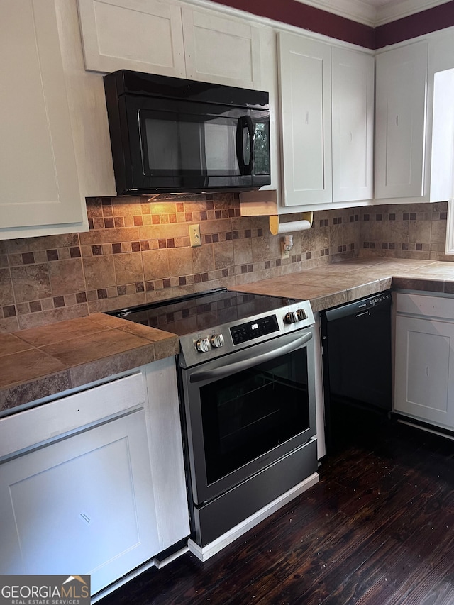 kitchen with white cabinets, tasteful backsplash, black appliances, and dark wood-type flooring