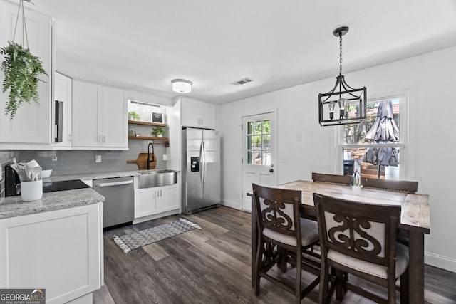 kitchen featuring appliances with stainless steel finishes, light stone counters, dark wood-type flooring, and white cabinetry