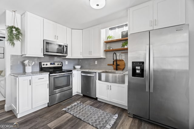 kitchen with decorative backsplash, light stone counters, appliances with stainless steel finishes, and dark wood-type flooring