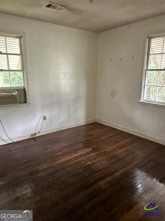 spare room featuring cooling unit, a healthy amount of sunlight, and wood-type flooring