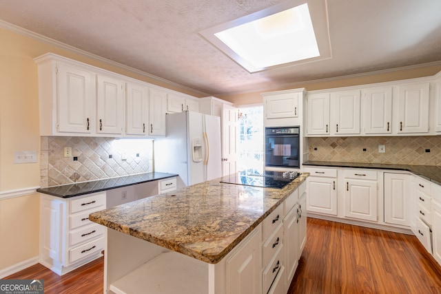 kitchen with wood-type flooring, crown molding, a kitchen island, black appliances, and white cabinetry