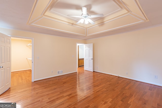 empty room with ornamental molding, ceiling fan, hardwood / wood-style floors, and a raised ceiling