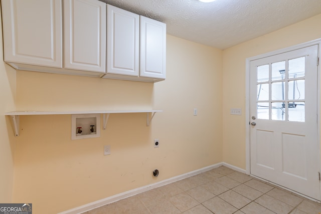 laundry room with light tile patterned flooring, a textured ceiling, cabinets, hookup for a washing machine, and electric dryer hookup