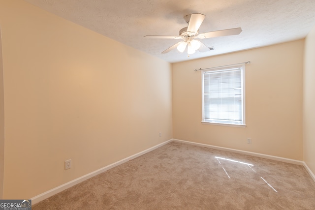 empty room with ceiling fan, light colored carpet, and a textured ceiling