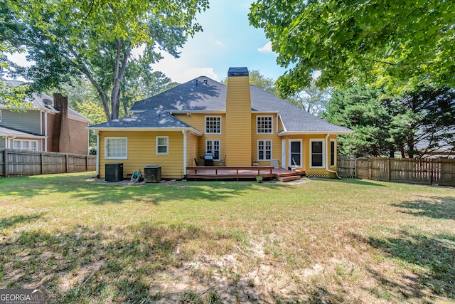 back of house featuring cooling unit, a wooden deck, and a yard