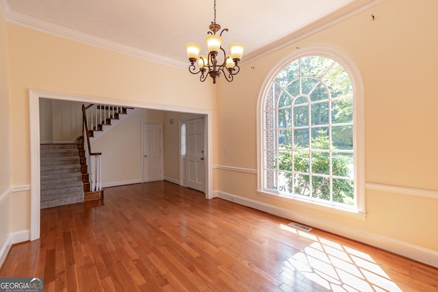 foyer featuring wood-type flooring, a notable chandelier, and crown molding