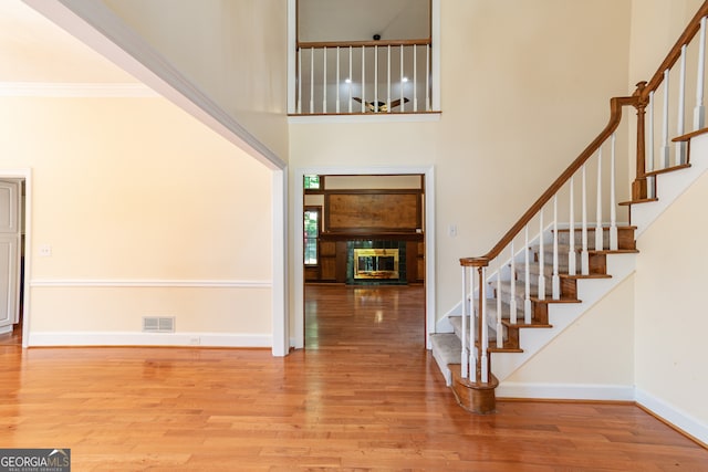 foyer featuring light hardwood / wood-style floors, a high ceiling, and ornamental molding