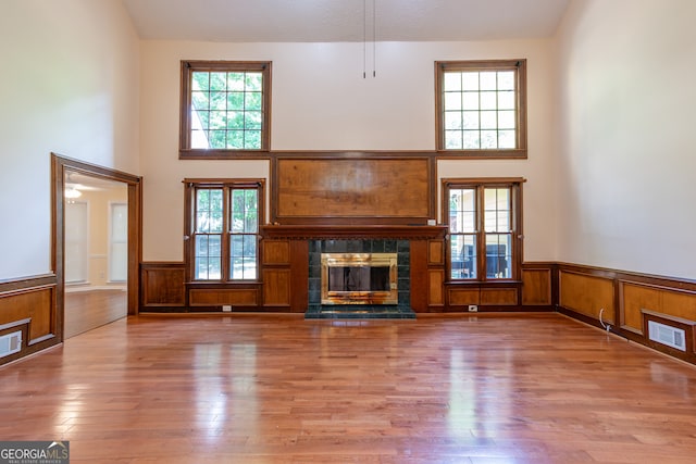 unfurnished living room featuring hardwood / wood-style flooring, a fireplace, and a towering ceiling