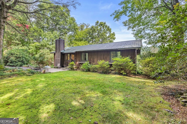 rear view of property featuring a lawn and a patio area