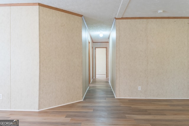 hall with wood-type flooring, a textured ceiling, and crown molding