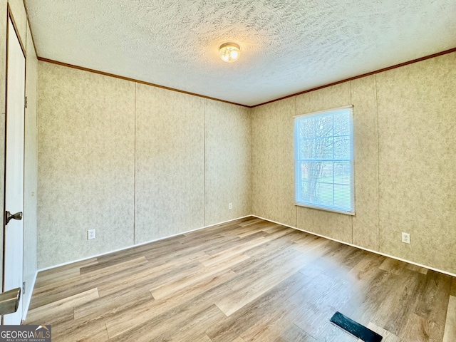 unfurnished room featuring hardwood / wood-style floors, a textured ceiling, and crown molding