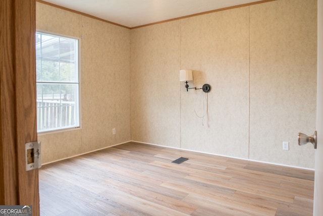 spare room with a wealth of natural light, light hardwood / wood-style flooring, and ornamental molding