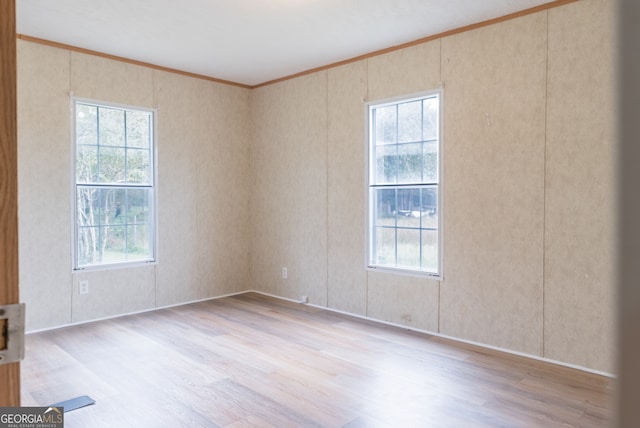 unfurnished room with plenty of natural light, ornamental molding, and light hardwood / wood-style flooring