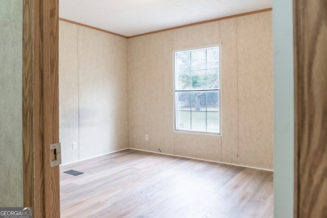 empty room featuring light wood-type flooring and crown molding