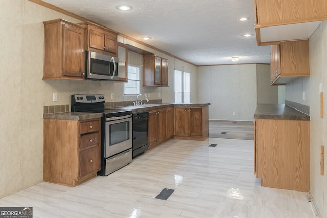 kitchen featuring sink, a textured ceiling, ornamental molding, and stainless steel appliances