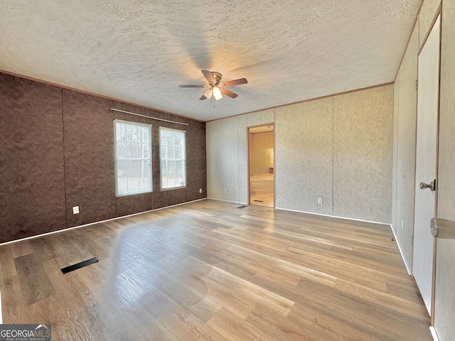 unfurnished bedroom featuring a textured ceiling, hardwood / wood-style flooring, ceiling fan, and ensuite bathroom