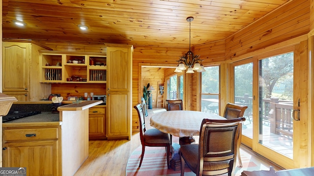 kitchen featuring light wood-type flooring, pendant lighting, wood ceiling, wooden walls, and an inviting chandelier