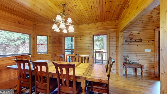 dining room featuring wood walls, an inviting chandelier, and light wood-type flooring